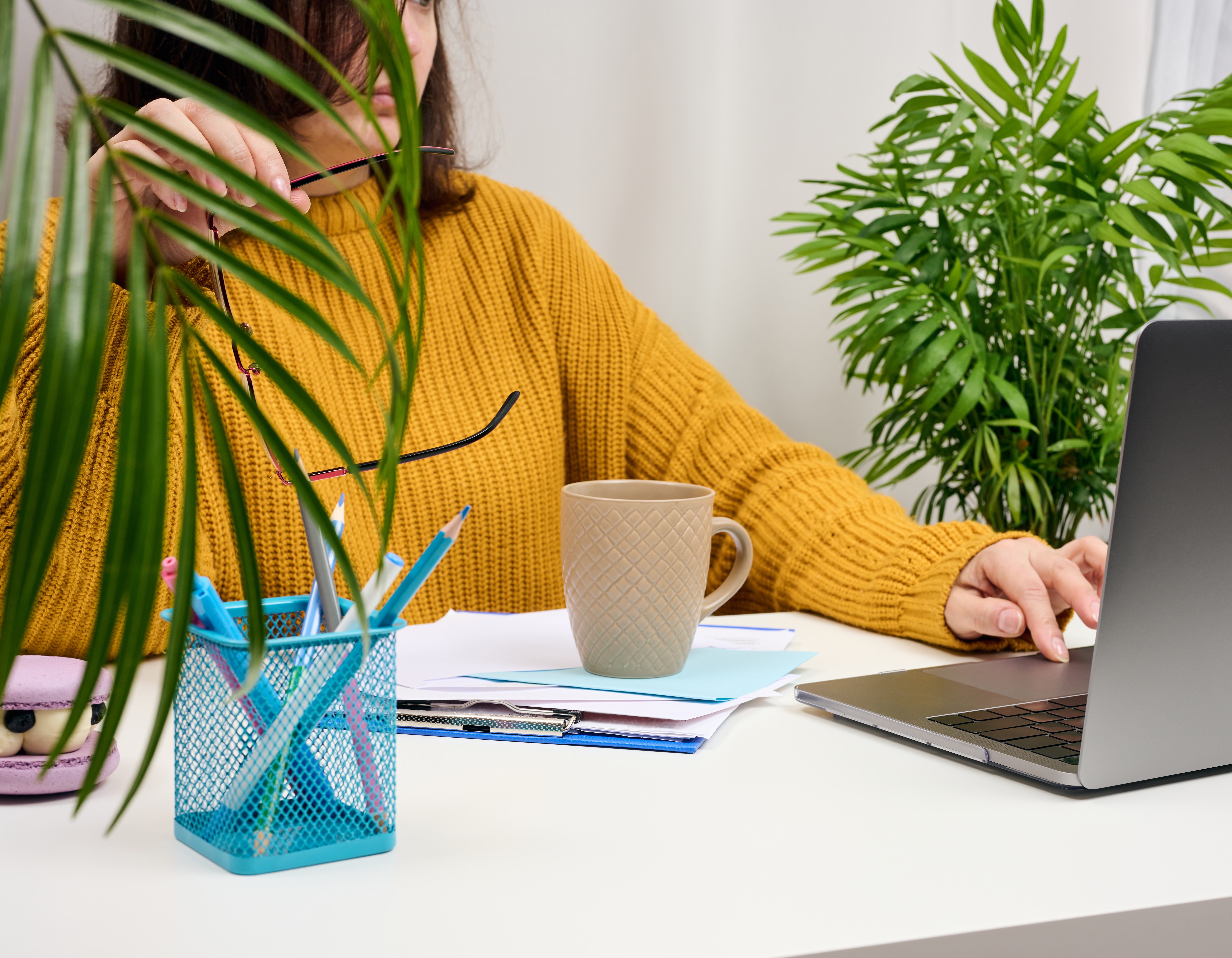 woman in a orange sweater sits at a table and works at a computer. Remote work, freelance. Online shopping